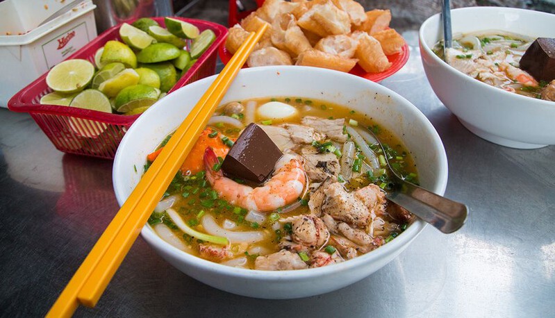 Crab Noodle Soup (Bánh Canh Cua) at Ben Thanh Market with fresh toppings and a thick, piping-hot broth.