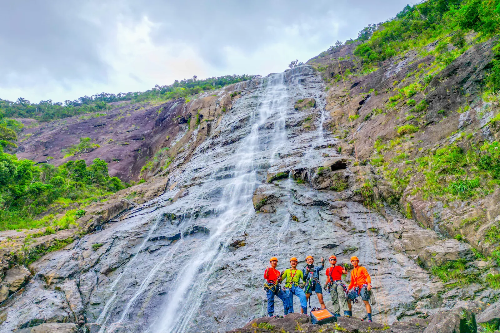 Majestic Do Quyen Waterfall in Bach Ma National Park, with water cascading down a rocky cliff.