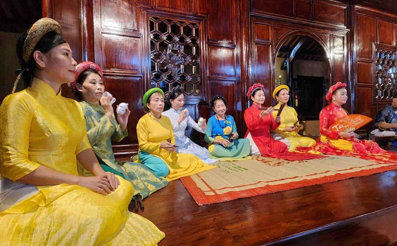 A group enjoying Hue Royal Court Music while relaxing on a dragon boat amidst a serene, rainy backdrop.